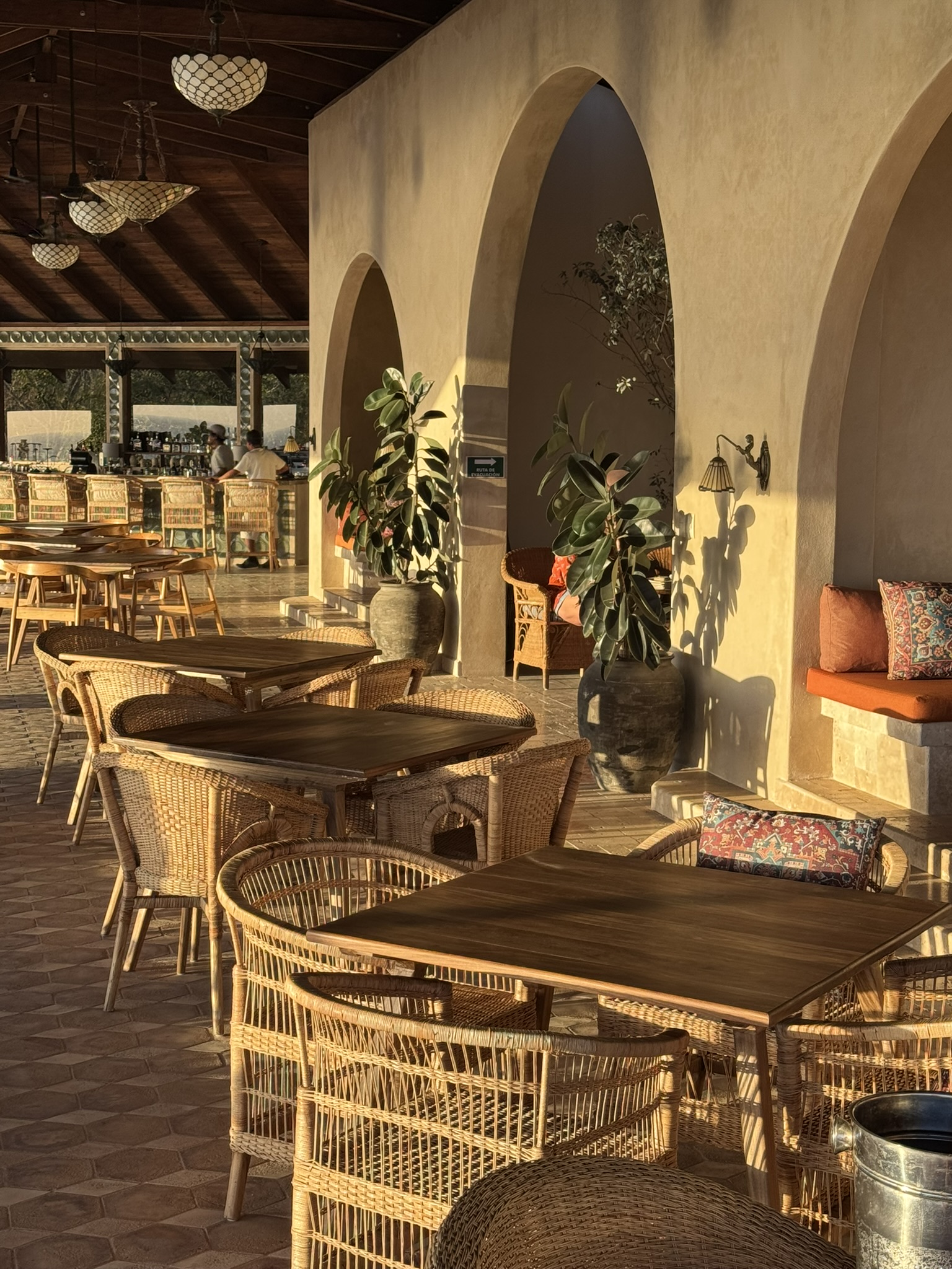 Dining area with wicker chairs and arches at golden hour